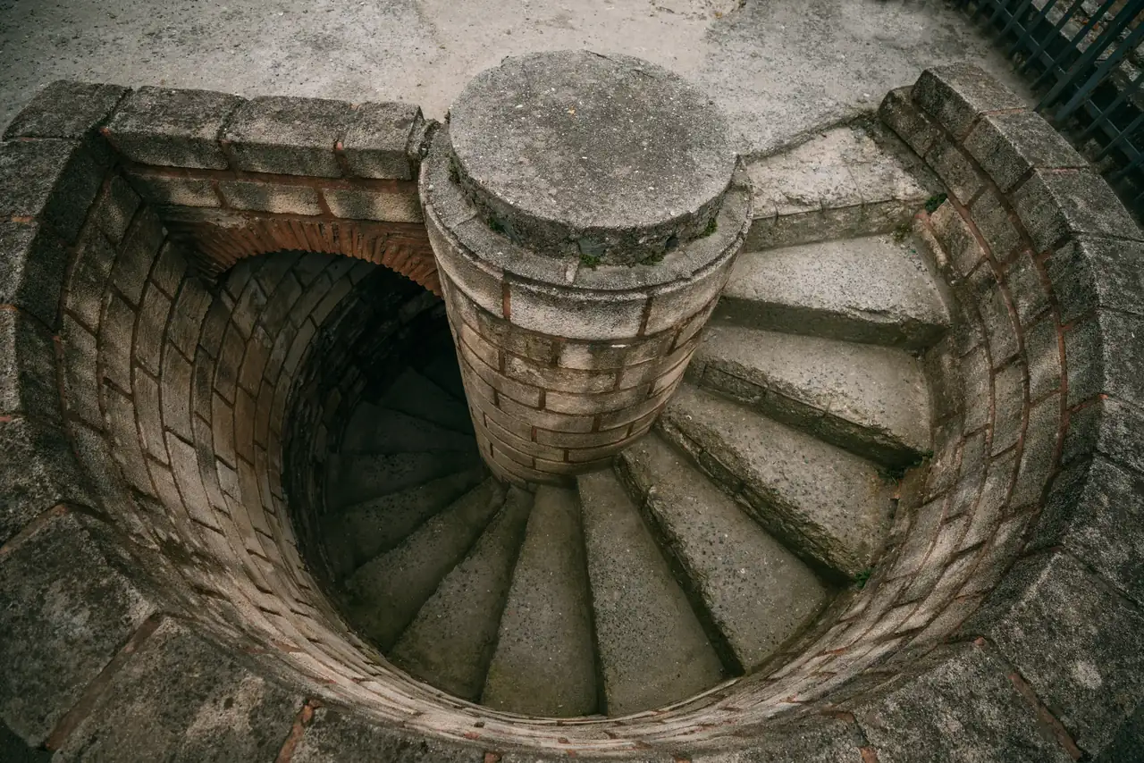 Stone spiral staircase seen from above, warm light